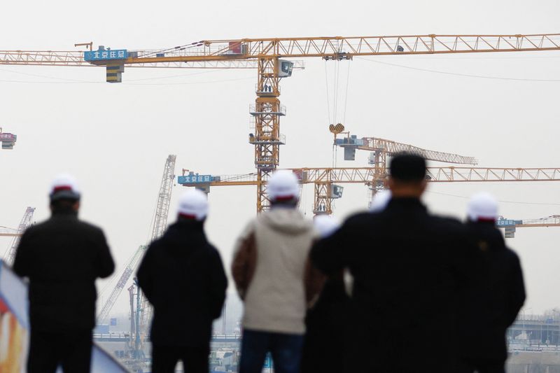 &copy; Reuters. People look on near cranes standing at a construction site in Beijing, China January 12, 2023. REUTERS/Tingshu Wang/Files