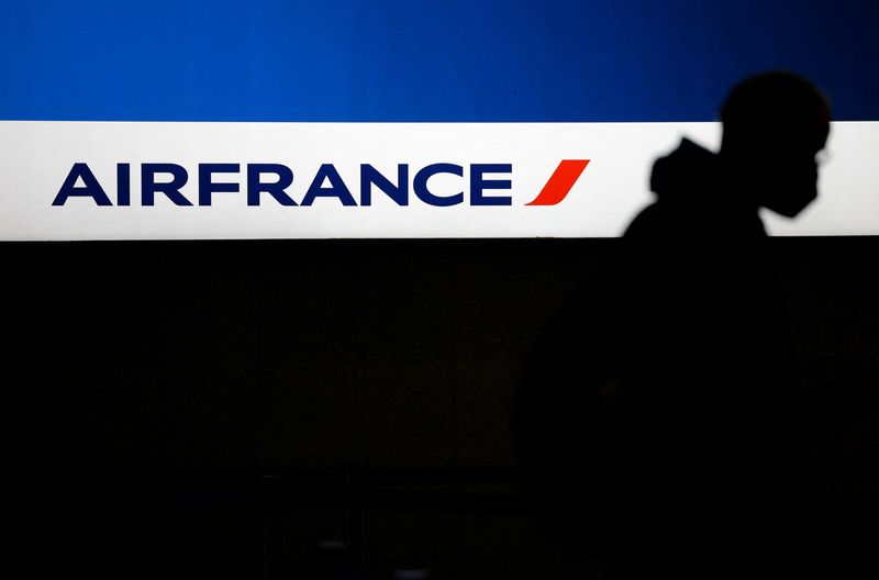 &copy; Reuters. FILE PHOTO-A passenger, wearing a protective face mask, walks past the logo of airline company Air France at the Nantes-Atlantique airport in Bouguenais near Nantes, France, June 29, 2022. REUTERS/Stephane Mahe
