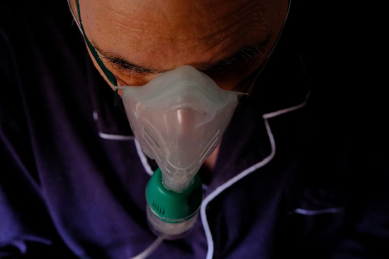 &copy; Reuters. Jose Maria Casais, 69, who is suffering from flu, uses an oxygen nebuliser as he sits on a wheelchair inside his house, in Barcelona, Spain, December 22, 2022. Casais, a retired engineer, says he is being forced to raid his savings every month after his e
