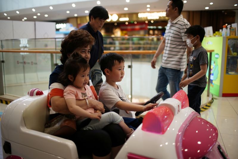 &copy; Reuters. A person holds a girl as a boy drives a toy car at a shopping mall in Shanghai, China June 1, 2021. REUTERS/Aly Song/File Photo