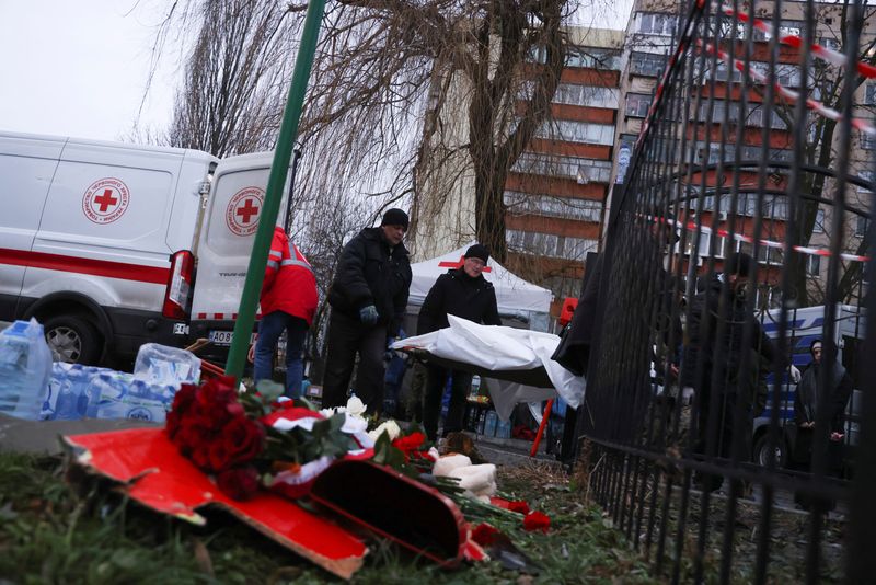 © Reuters. Ritual workers carry bodies of victims as they walk past tributes for victims, near the site of a helicopter crash, amid Russia's attack on Ukraine, in the town of Brovary, outside Kyiv, Ukraine, January 18, 2023. REUTERS/Nacho Doce