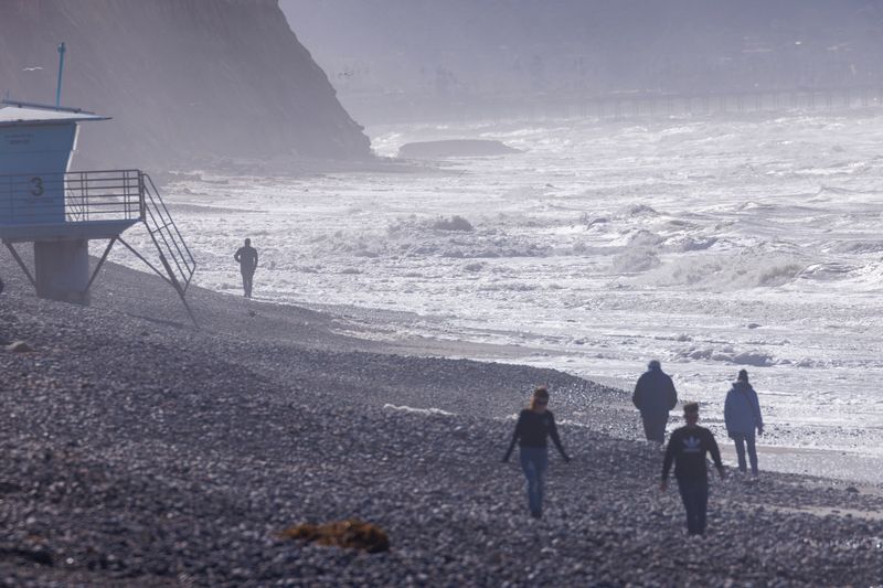 &copy; Reuters. FILE PHOTO: People walk along a rocky beach caused by high surf following winter storms in San Diego, California, U.S., January 17, 2023.   REUTERS/Mike Blake