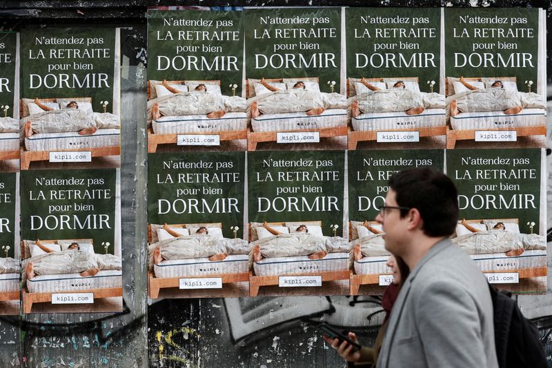 © Reuters. Des gens passent devant des affiches à Paris protestant contre le plan de réforme des retraites en France. /Photo prise le 19 janvier 2022/REUTERS/Benoit Tessier