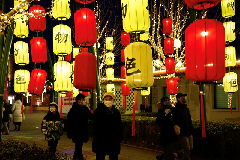 &copy; Reuters. Diversi passanti per una strada illuminata da lanterne per il Capodanno lunare a Pechino. REUTERS/Tingshu Wang