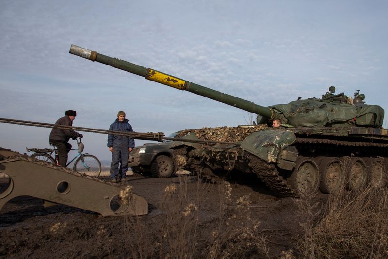 © Reuters. A Ukrainian serviceman looks on and a local resident rides a bicycle while a broken tank is pulled to a truck near the frontline town of Bakhmut, amid Russia's attack on Ukraine, in Donetsk region, Ukraine January 20, 2023. REUTERS/Oleksandr Ratushniak