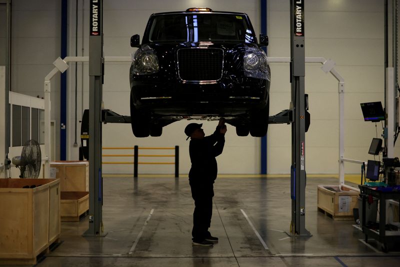 © Reuters. A worker stands beneath a TX electric taxi inside the LEVC (London Electric Vehicle Company) factory in Coventry, Britain, January 18, 2023. REUTERS/Phil Noble