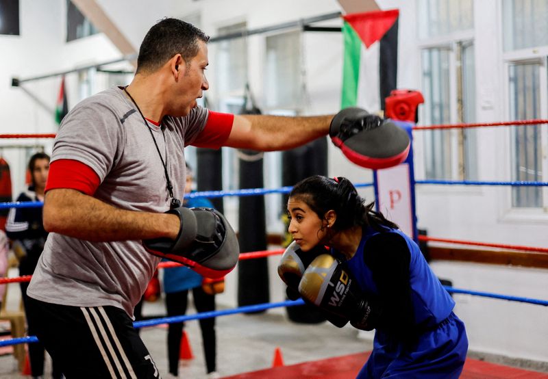 &copy; Reuters. فتاة فلسطينية تدعي فرح أبو القمصان مع مدربها أسامة أيوب خلال التدريب داخل أول مركز ملاكمة نسائي في مدينة غزة يوم 17 يناير كانون الثاني 2023. تصو