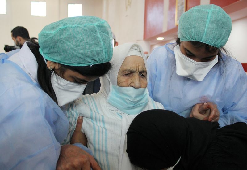 &copy; Reuters. عاملون في قطاع الرعاية الصحية يساعدون امرأة مسنة خلال حملة تطعيم ضد فيروس كوفيد-19 في مدينة سلا المغربية. صورة من أرشيف رويترز.
