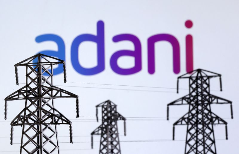 © Reuters. FILE PHOTO: Electric power transmission pylon miniatures and Adani Green Energy logo are seen in this illustration taken, December 9, 2022. REUTERS/Dado Ruvic/Illustration