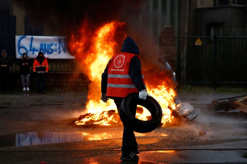 © Reuters. French energy workers on strike gather with dockers near tyres set on fire as they protest against French government's pension reform plan, in the port of Saint-Nazaire, France, January 26, 2023. The banner reads 