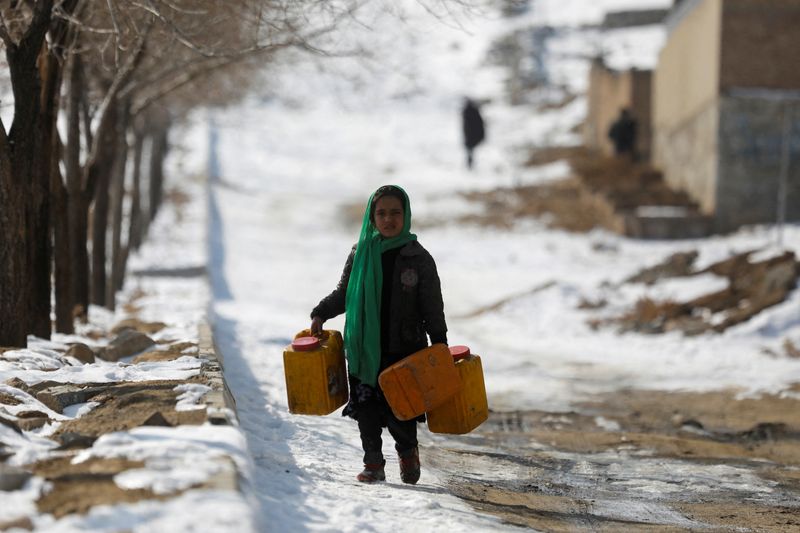 © Reuters. An Afghan girl carries empty water containers on a snow-covered street in Kabul, Afghanistan, January 26, 2023. REUTERS/Ali Khara 