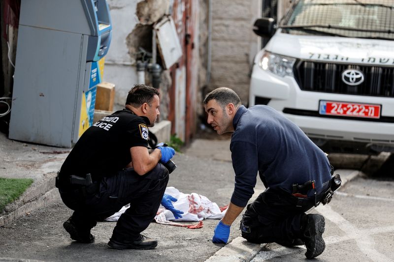&copy; Reuters. رجلا شرطة إسرائيليان بجانب قطعة قماش ملطخة بالدماء قرب موقع إطلاق نار خارج المدينة القديمة في القدس يوم السبت. تصوير: عمار عوض - رويترز.
