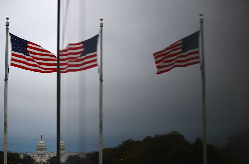 &copy; Reuters. Le Capitole des États-Unis et les drapeaux américains se reflètent dans une fenêtre à Washington. /Photo prise le 29 octobre 2020/REUTERS/Hannah McKay