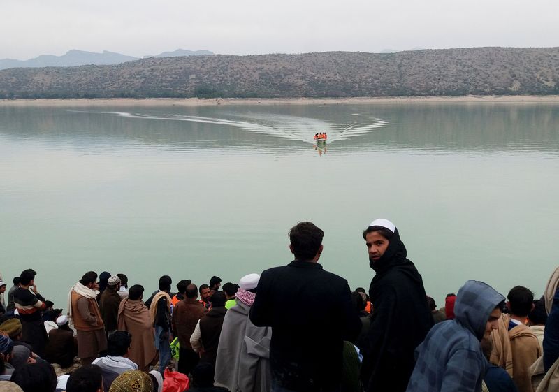 &copy; Reuters. People gather as rescue workers search for the victims, after a boat carrying religious school students capsized in Tanda lake in Kohat, Pakistan January 29, 2023. REUTERS/Stringer