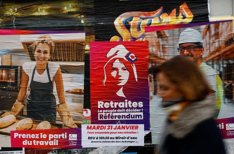 © Reuters. A woman walks in front of a poster calling for the demonstration against the pension reform in Reze near Nantes, France, January 30, 2023. REUTERS/Stephane Mahe