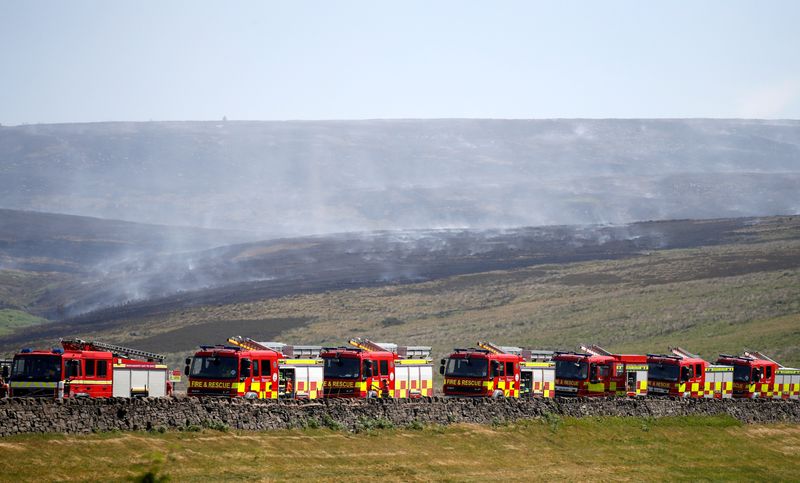 © Reuters. FILE PHOTO: Fire engines park up on the moor as firefighters continue tackling a blaze on Saddleworth Moor, Britain, June 28, 2018. REUTERS/Phil Noble