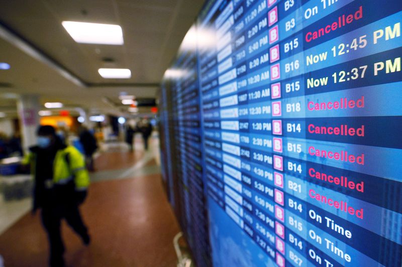 © Reuters. FILE PHOTO: A board displays the status of flights to and from Logan International Airport, amid cancellations and disruptions due to adverse weather and the surge in coronavirus cases caused by the Omicron variant, in Boston, Massachusetts, U.S., January 3, 2022.   REUTERS/Brian Snyder