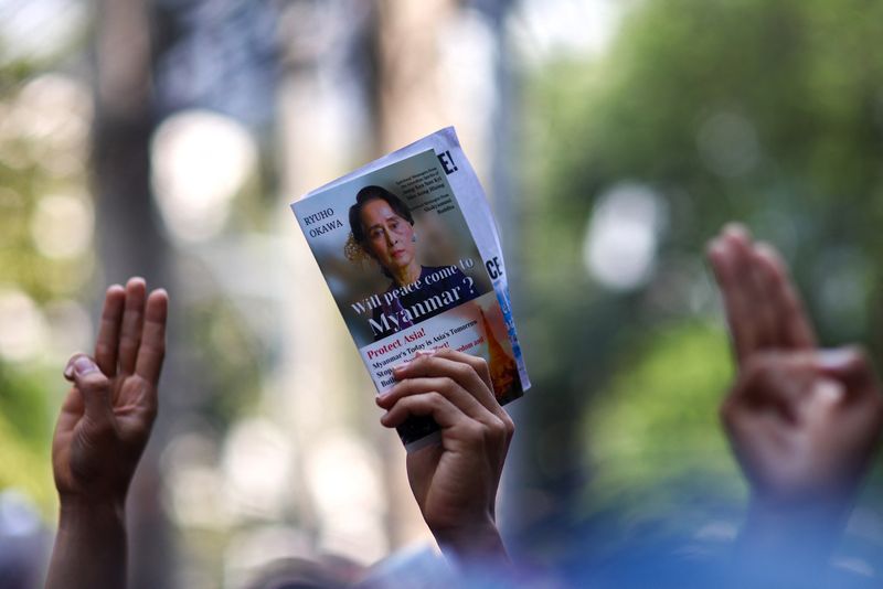 © Reuters. A protester holds up a picture of Aung San Suu Kyi while others hold up three-finger salutes, during a demonstration to mark the second anniversary of Myanmar's 2021 military coup, outside the Embassy of Myanmar in Bangkok, Thailand, February 1, 2023. REUTERS/Athit Perawongmetha