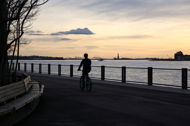 &copy; Reuters. FILE PHOTO: A person rides a bike as the sunset over Manhattan is seen from Brooklyn Bridge Park, during the outbreak of the coronavirus disease (COVID-19) in Brooklyn, New York City, U.S., March 24, 2020. REUTERS/Caitlin Ochs