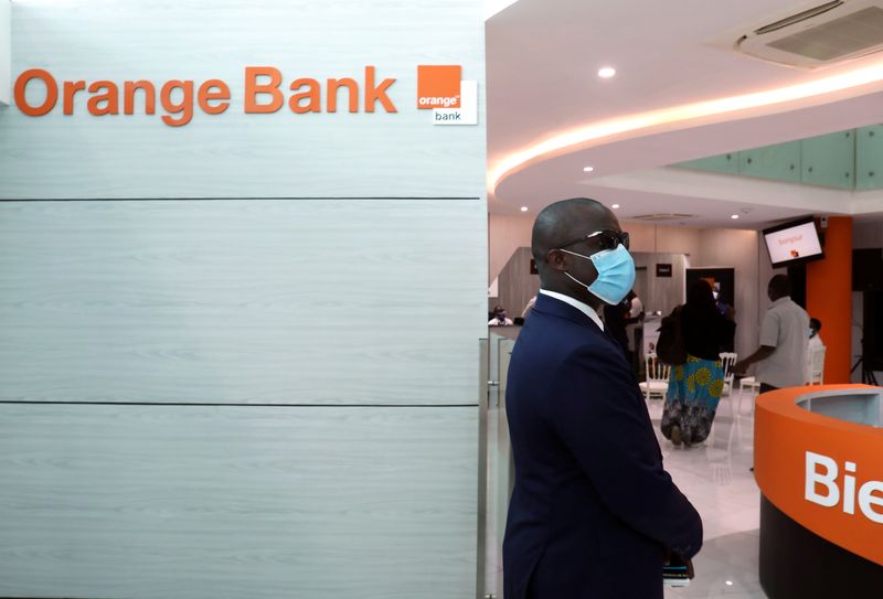 &copy; Reuters. Un homme se tient à l'intérieur du premier bâtiment des services Orange Bank de l'opérateur mobile français Orange à Abidjan, en Côte d'Ivoire. /Photo d'archive/REUTERS/Luc Gnago