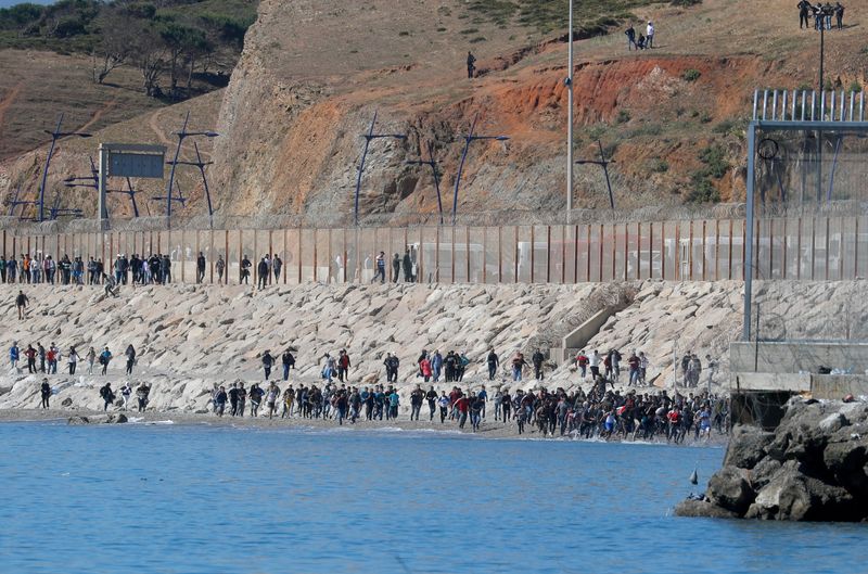 &copy; Reuters. FILE PHOTO: Migrants run towards the fence separating Morocco from Spain, after thousands of migrants swam across the border, in Ceuta, Spain, May 19, 2021. REUTERS/Jon Nazca/File Photo