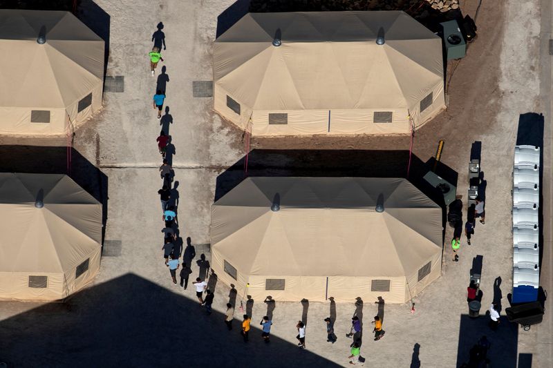 © Reuters. FILE PHOTO: Immigrant children are led by staff in single file between tents at a detention facility next to the Mexican border in Tornillo, Texas, U.S., June 18, 2018.  REUTERS/Mike Blake  