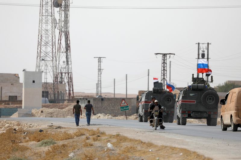 &copy; Reuters. مركبات عسكرية تحمل الأعلام السورية والروسية في منطقة قريبة من منبج بسوريا. صورة من أرشيف رويترز