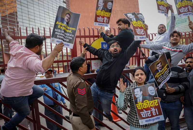 © Reuters. Activists of the youth wing of India's main opposition Congress party shout slogans as they cling to the gate of Life Insurance Corporation (LIC) office during a protest against what they say are investments by the LIC and State Bank of India (SBI) in the Adani Group, in New Delhi, India, February 7, 2023. REUTERS/Adnan Abidi