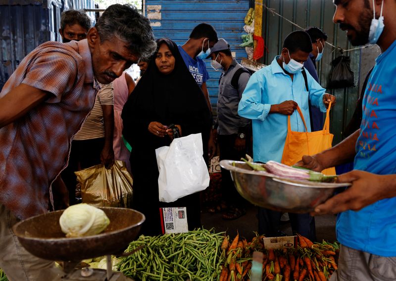 © Reuters. FILE PHOTO: A woman buys vegetables from a vendor at a market in the rampant food inflation, amid Sri Lanka's economic crisis, in Colombo, Sri Lanka, July 30 , 2022. REUTERS/Kim Kyung-Hoon