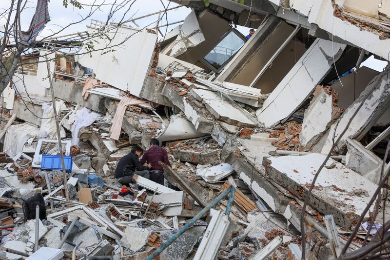 &copy; Reuters. أشخاص يقفون على أنقاض منزل مدمر للبحث عن ناجين بعد الزلزال الذي وقع في مقاطعة هاتاي بتركيا يوم الثلاثاء. تصوير: أوكيت بكطاش - رويترز.