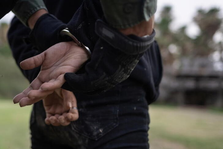 © Reuters. A U.S. border patrol agent handcuffs a migrant woman after she was found hiding in thick brush after crossing the Rio Grande river into the United States from Mexico in La Joya, Texas, U.S., May 18, 2021. REUTERS/Adrees Latif