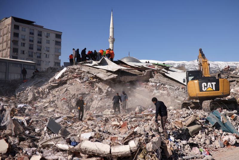 &copy; Reuters. أشخاص يعملون في موقع مبنى منهار جراء الزلزال في منطقة كهرمان مرعش بتركيا يوم الأربعاء. تصوير: ستويان نينوف – رويترز.