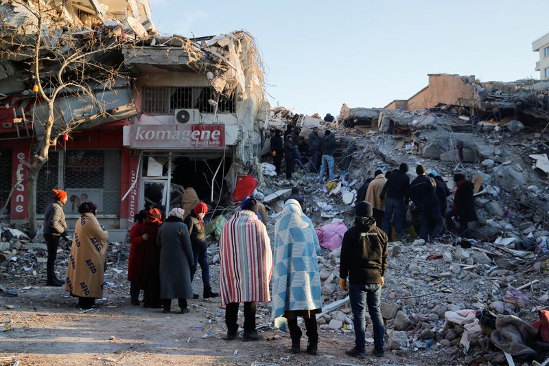 &copy; Reuters. أشخاص يقفون أمام مبنى مدمر عقب الزلزال في منطقة كهرمان مرعش بتركيا يوم الأربعاء. تصوير: ديلارا سنكايا - رويترز.