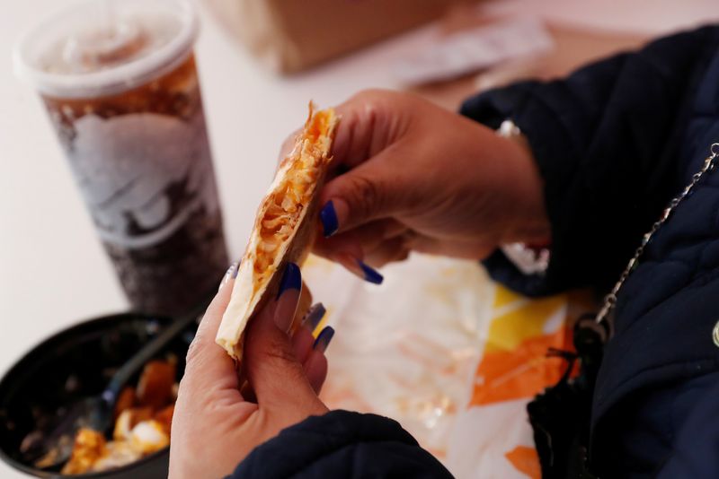 © Reuters. FILE PHOTO: A woman eats Taco Bell inside the first digital-only U.S. cantina location at Times Square in New York City, U.S., April 14, 2021. REUTERS/Shannon Stapleton