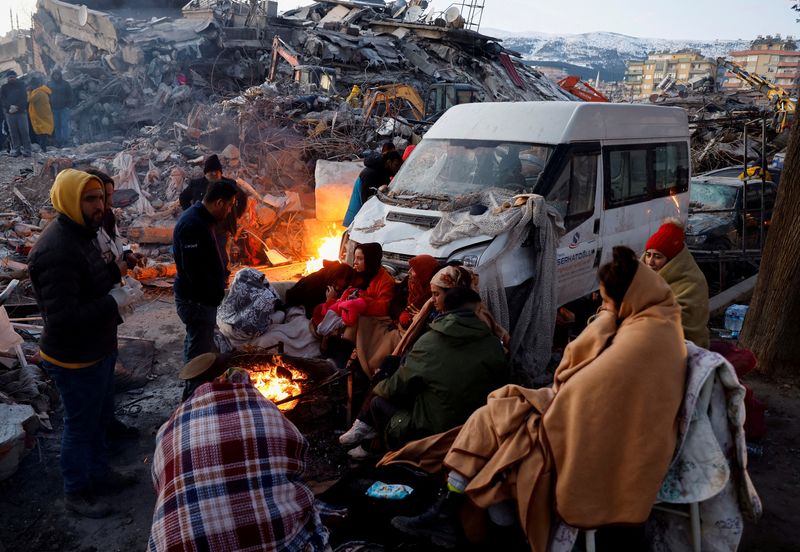&copy; Reuters. أشخاص يجلسون بجوار أنقاض مبنى منهار في منطقة قهرمان مرعش في أعقاب زلزال مدمر هز تركيا يوم الأربعاء. تصوير: صهيب سالم - رويترز.