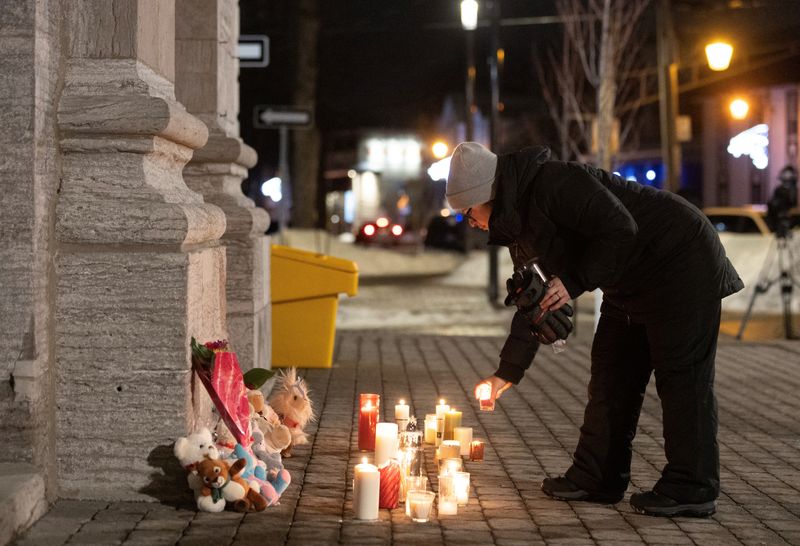 © Reuters. A person lights a candle during a vigil outside a church close to the site where a Laval city bus crashed into the daycare,  in Laval, Quebec, February 8, 2023. REUTERS/Christinne Muschi