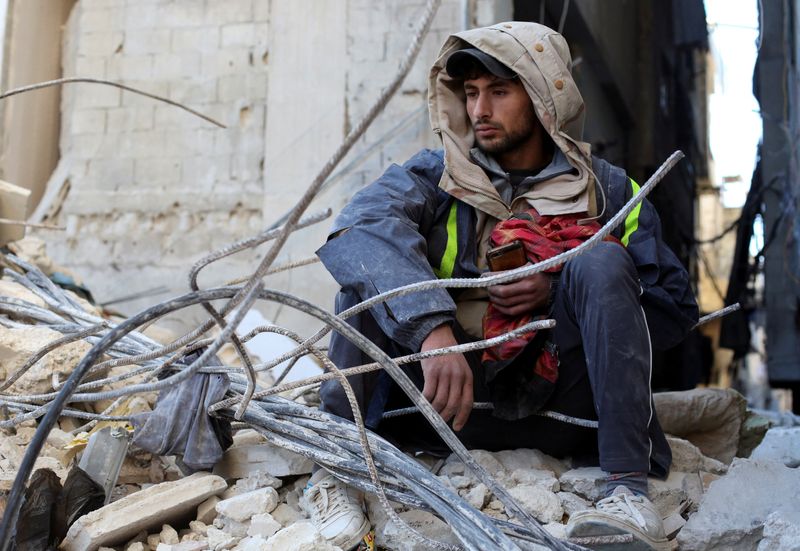 &copy; Reuters. شخص يجلس وسط ركام منزل متضرر جراء الزلزال في محافظة اللاذقية السورية يوم الخميس. تصوير: يمام الشعار – رويترز.