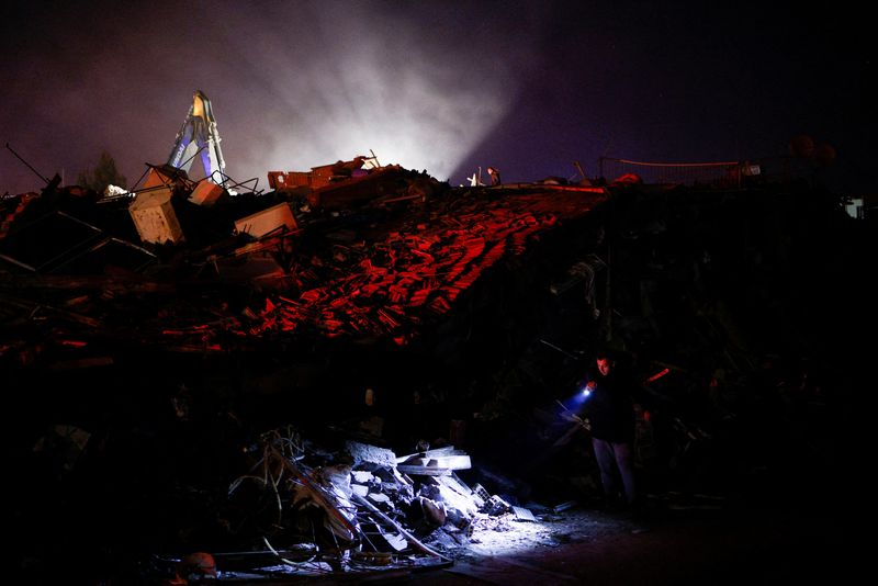 © Reuters. A man uses a lintern to check damaged buildings, in the aftermath of an earthquake, in Antakya, Turkey, February 8, 2023. REUTERS/Guglielmo Mangiapane 