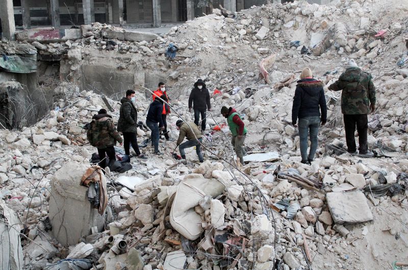 © Reuters. أشخاص يقفون فوق أنقاض أحد المباني المنهارة في حلب يوم الخميس بينما يستمر البحث عن ناجين من الزلزال الذي ضرب سوريا. تصوير : فراس مقدسي - رويترز . 
  