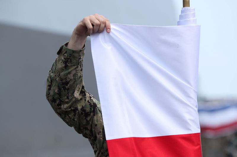 &copy; Reuters. Un soldat américain déroule un drapeau de la Pologne, à Gdynia. /Photo prise le 7 juin 2022/REUTERS/Kacper Pempel