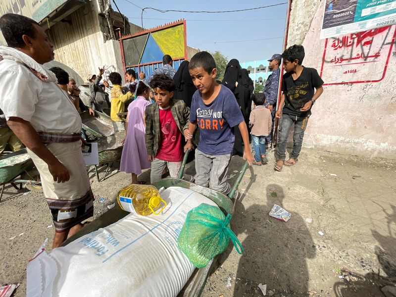 &copy; Reuters. طفل يدفع عربة تحتوي على جوال من الدقيق و زجاجة زيت طعام وكيس يحتوي على الفول حصل عليها من مركز لتوزيع المساعدات الغذائية في العاصمة اليمنية 