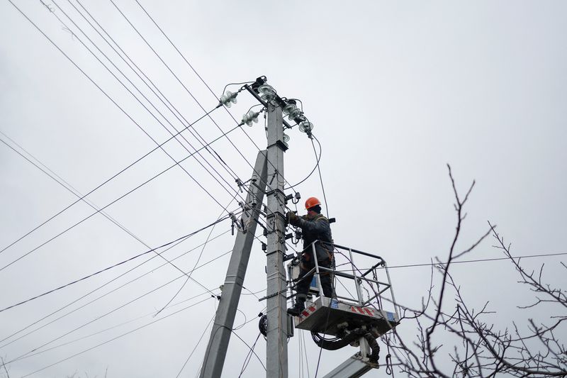 &copy; Reuters. FILE PHOTO: An employee of power supplier repairs power lines in front of residential houses damaged by a Russian military strike, amid Russia's attack on Ukraine, in the town of Hlevakha, outside Kyiv, Ukraine January 26, 2023.  REUTERS/Valentyn Ogirenko