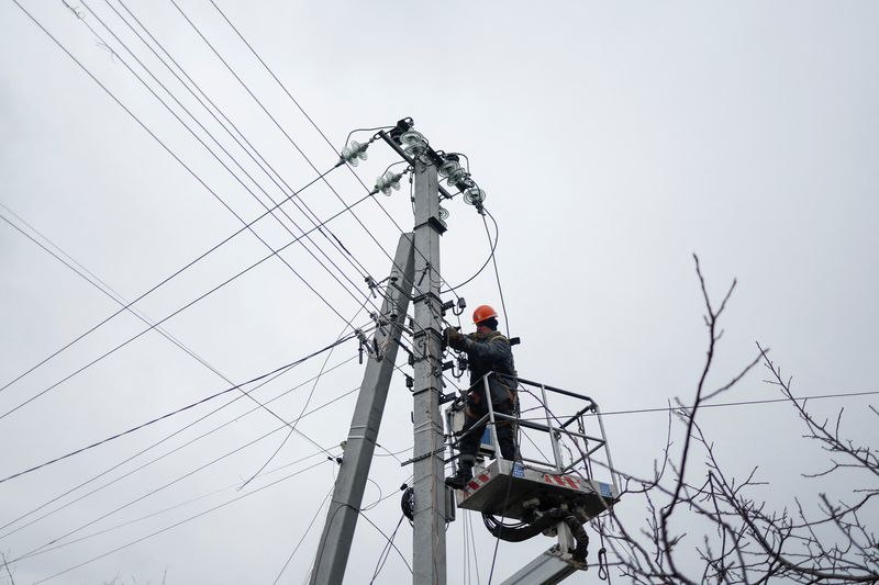 &copy; Reuters. FOTO DE ARCHIVO: Un empleado del proveedor de energía repara líneas eléctricas frente a casas residenciales dañadas por un ataque militar ruso, en medio del ataque de Rusia a Ucrania, en la ciudad de Hlevakha, en las afueras de Kiev, Ucrania. 26 de en