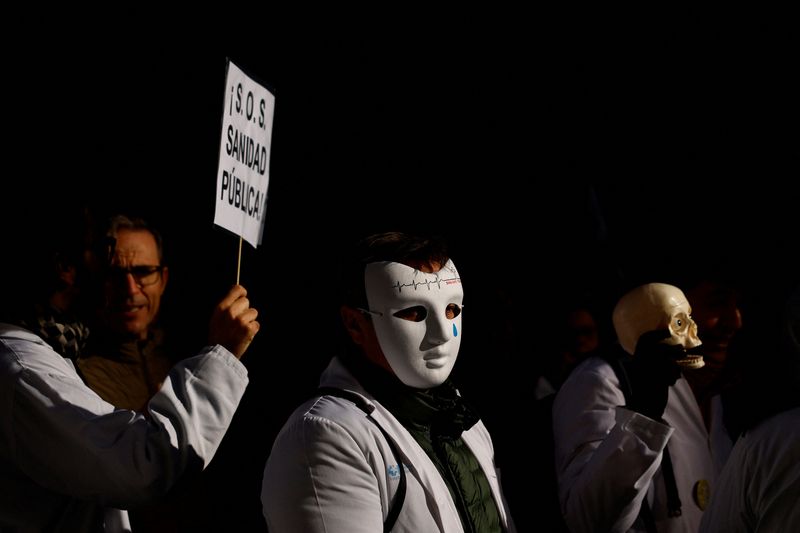 &copy; Reuters. عمال في مجال الرعاية الصحية يحملون لافتة مكتوب عليها " أنقذوا الرعاية الصحية" خلال احتجاجات على الرواتب وظروف العمل في مدريد يوم 18 يناير كان