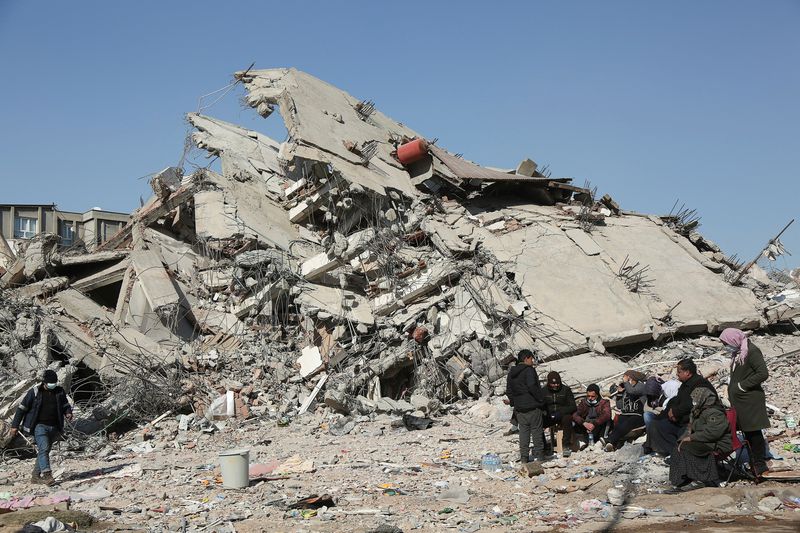 &copy; Reuters. FILE PHOTO: People sit and stand near a collapsed building, in the aftermath of the deadly earthquake, in Adiyaman, Turkey, February 12, 2023. REUTERS/Sertac Kayar