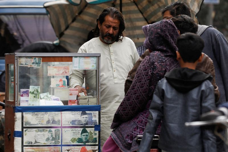 &copy; Reuters. FILE PHOTO: A currency broker stands near his booth, which is decorated with pictures of currency notes, while dealing with customers, along a road in Karachi, Pakistan January 27, 2023. REUTERS/Akhtar Soomro/File Photo