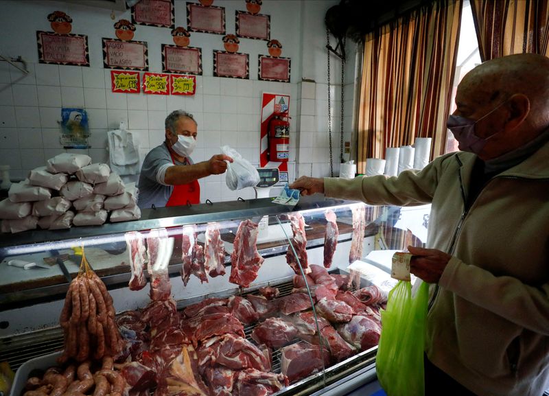 &copy; Reuters. FILE PHOTO: Butcher Hector, 59, handles meat to a customer, as he pays to him at his shop, as inflation in Argentina hits its highest level in years, causing food prices to spiral, in Buenos Aires, Argentina September 13, 2022. REUTERS/Agustin Marcarian