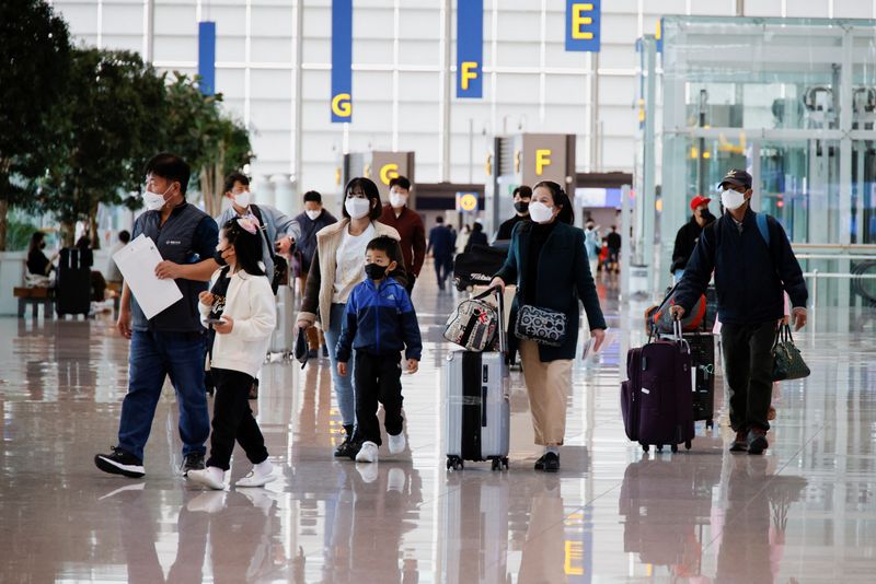 &copy; Reuters. Des personnes portant des masques faciaux pour éviter de contracter la maladie du coronavirus (COVID-19) marchent à l'aéroport international d'Incheon, en Corée du Sud. /Photo prise le 25 mars 2022/REUTERS/Heo Ran