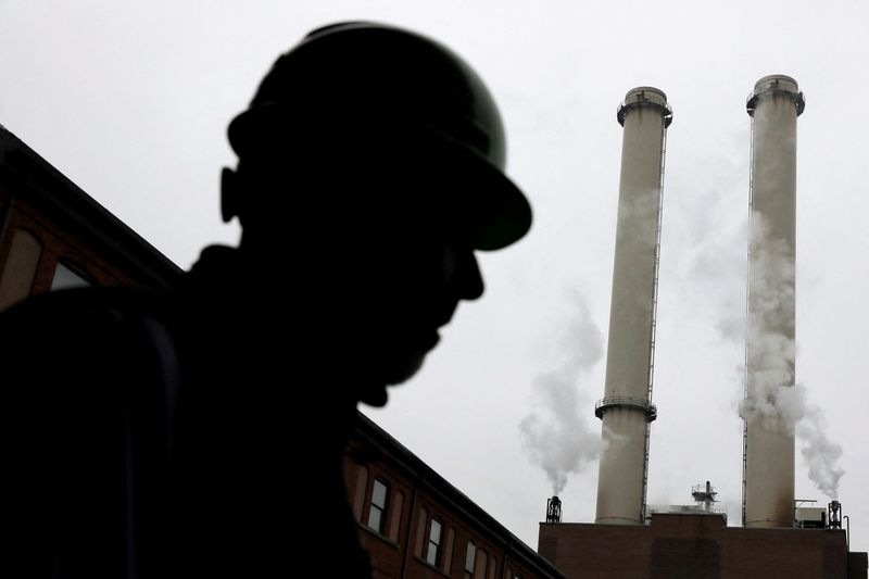 &copy; Reuters. FILE PHOTO: A worker stands near the chimney stacks of a neighbouring factory at IceStone, a manufacturer of recycled glass countertops and surfaces, in New York City, New York, U.S., June 3, 2021. REUTERS/Andrew Kelly/File Photo