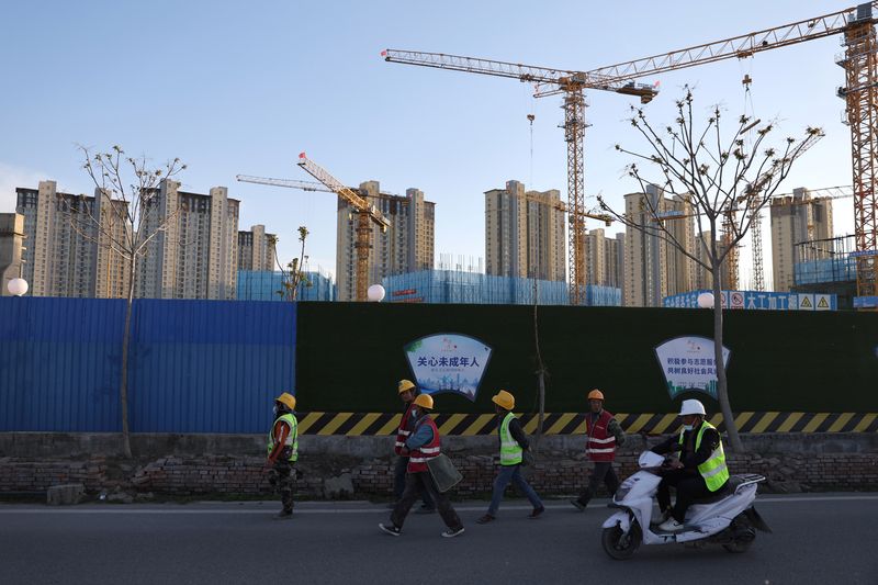 &copy; Reuters. Workers walk past a construction site near residential buildings in Beijing, China April 14, 2022. Picture taken April 14, 2022. REUTERS/Tingshu Wang/File Photo